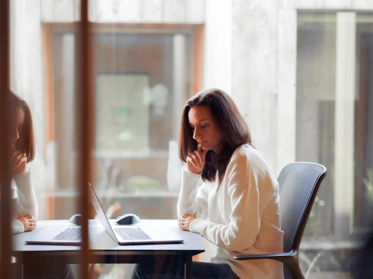 A woman sitting at a table with a laptop computer