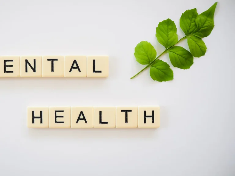 The word mental health spelled with scrabbles next to a green leaf