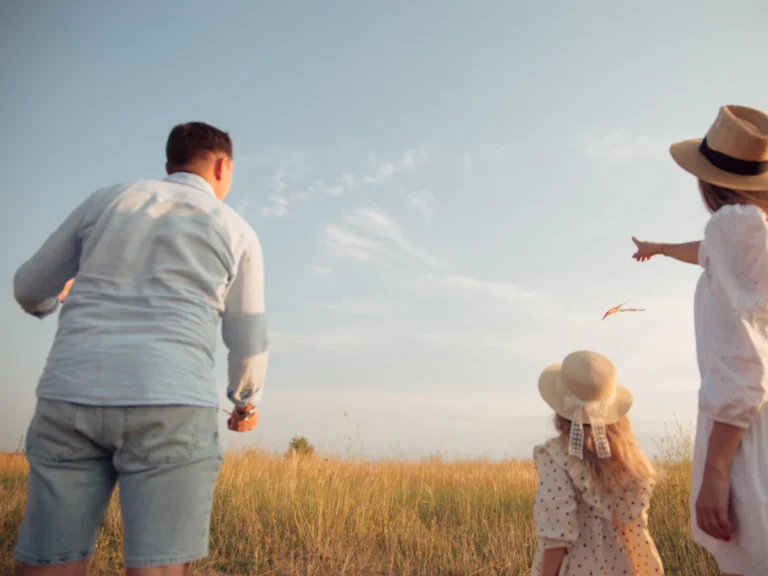 A family in a field flying a kite under a clear blue sky