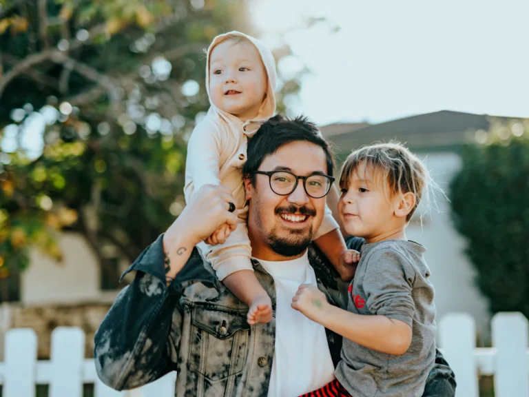 Man in white shirt carrying girl in gray shirt