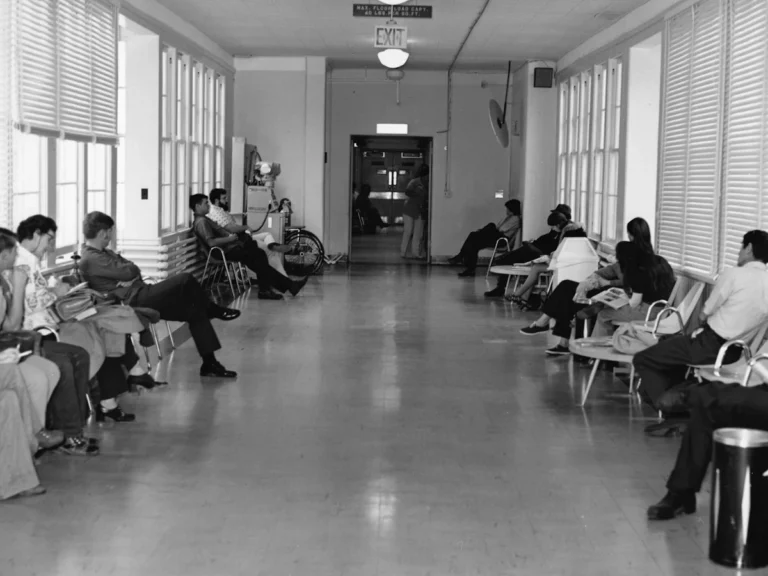 People waiting in a hallway with chairs and chairs