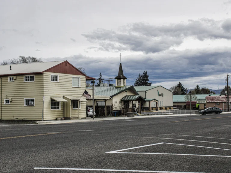 A street with a few buildings and a car parked on the side of the road