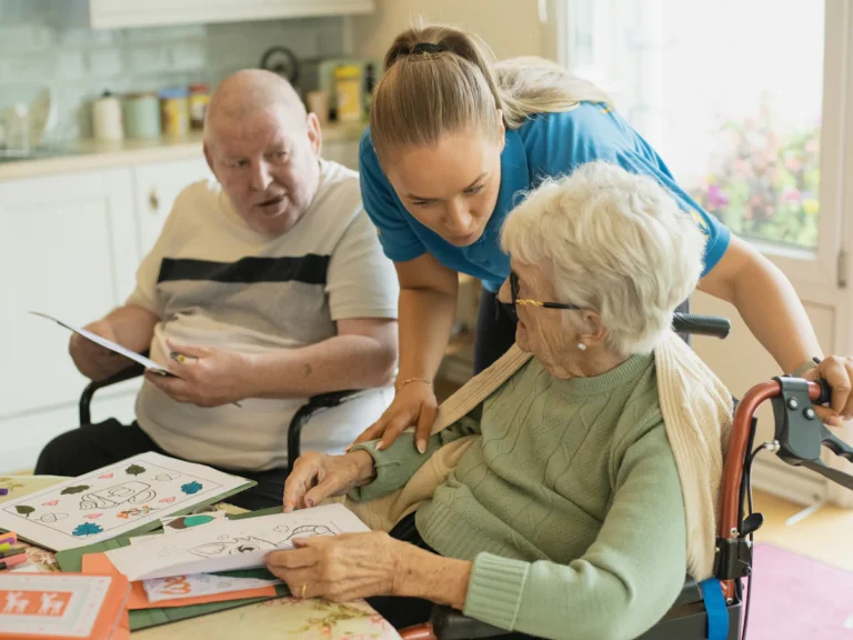 Caregiver assisting elderly couple with coloring
