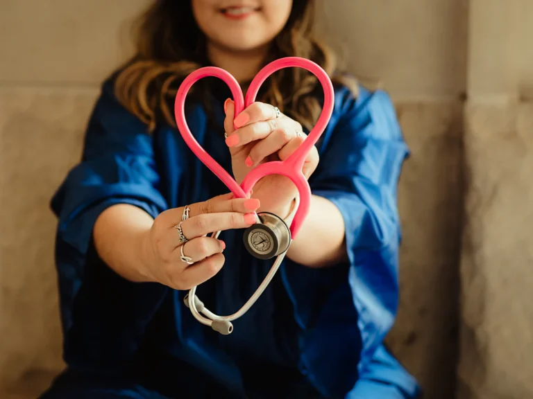 Woman in scrubs holding heart shaped stethoscope