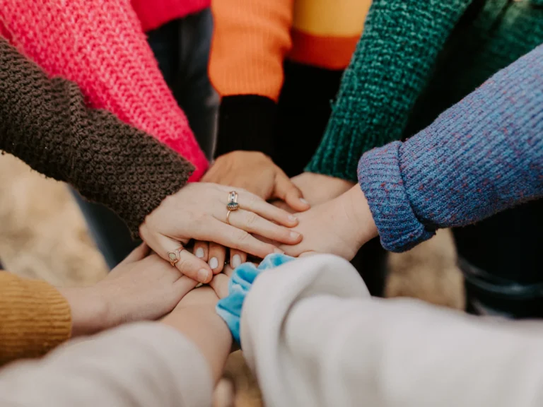 Group stacking hands in colorful sweaters