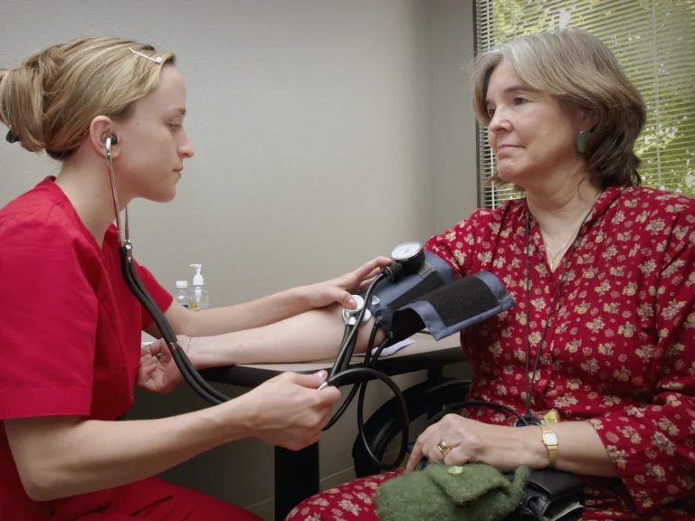 A woman with a stethoscope listening to a patient